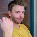 Een blonde man die goedkeurend kijkt.