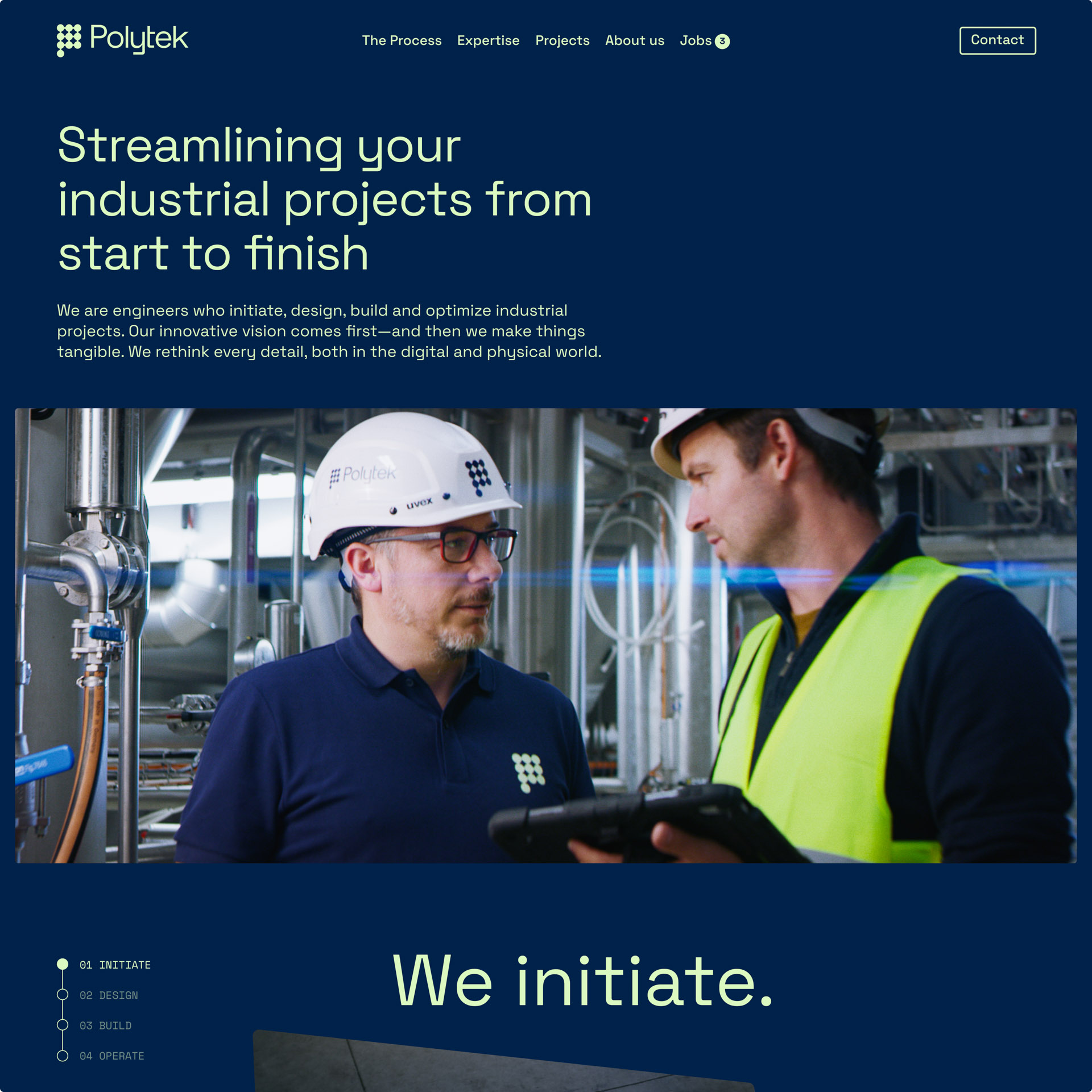 Twee ingenieurs in helmen, één met een Polytek-helm en blauwe polo, de ander in een gele veiligheidsvest, overleggen in een industriële fabriek met leidingen.