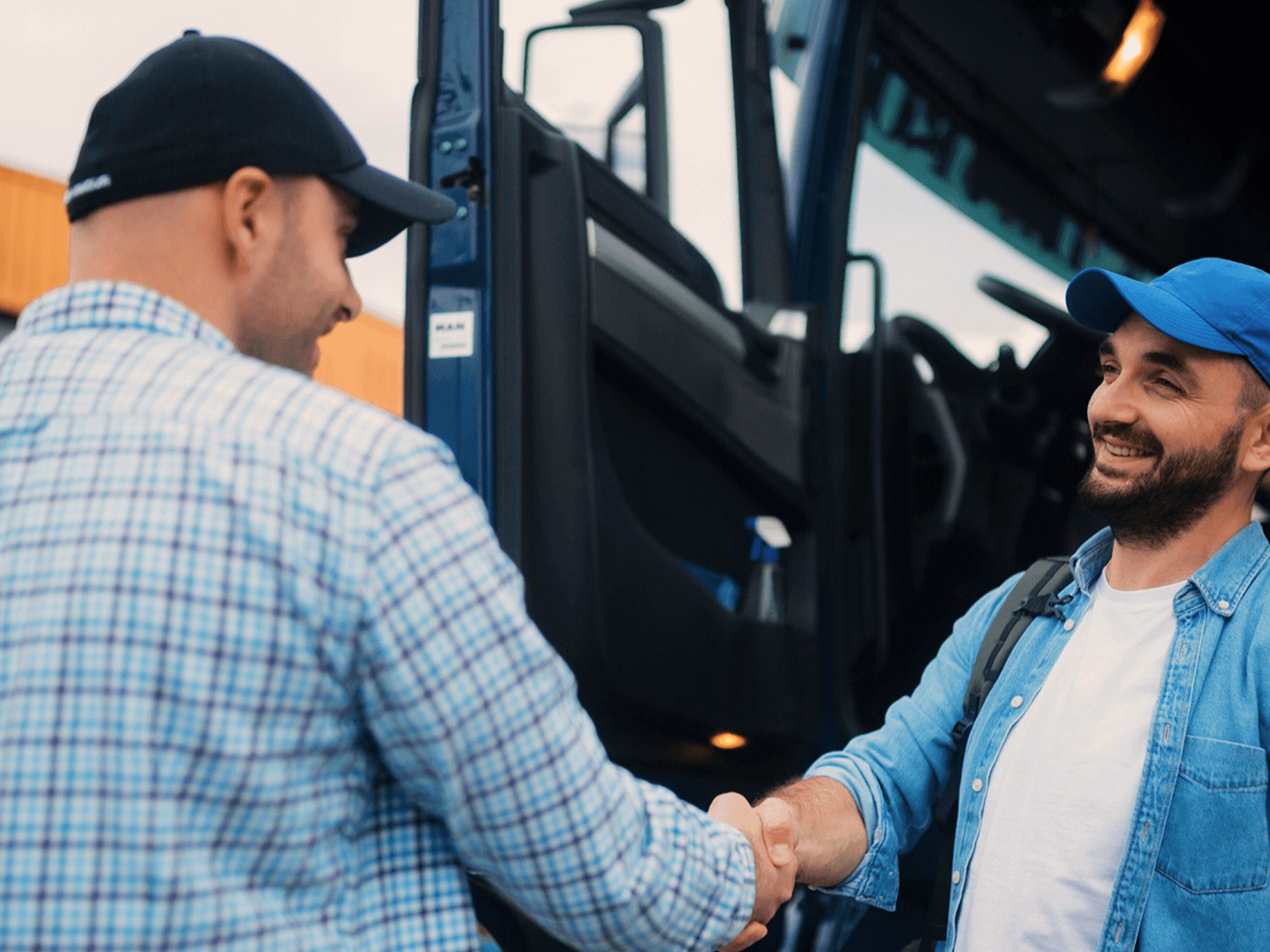 Two people shaking hands beside a truck cab.