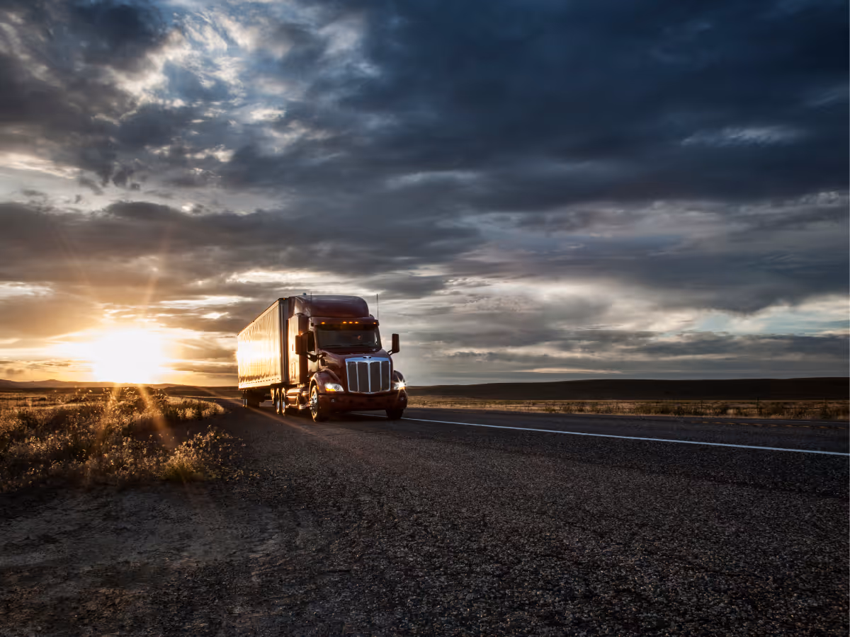 Semi-truck driving down the highway at sunset