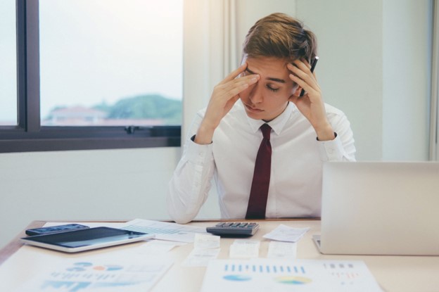 Frustrated office worker reviewing invoices and financial documents at a desk.