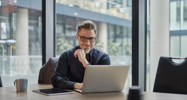 Business professional reviewing freight invoice data on a laptop in an office setting.