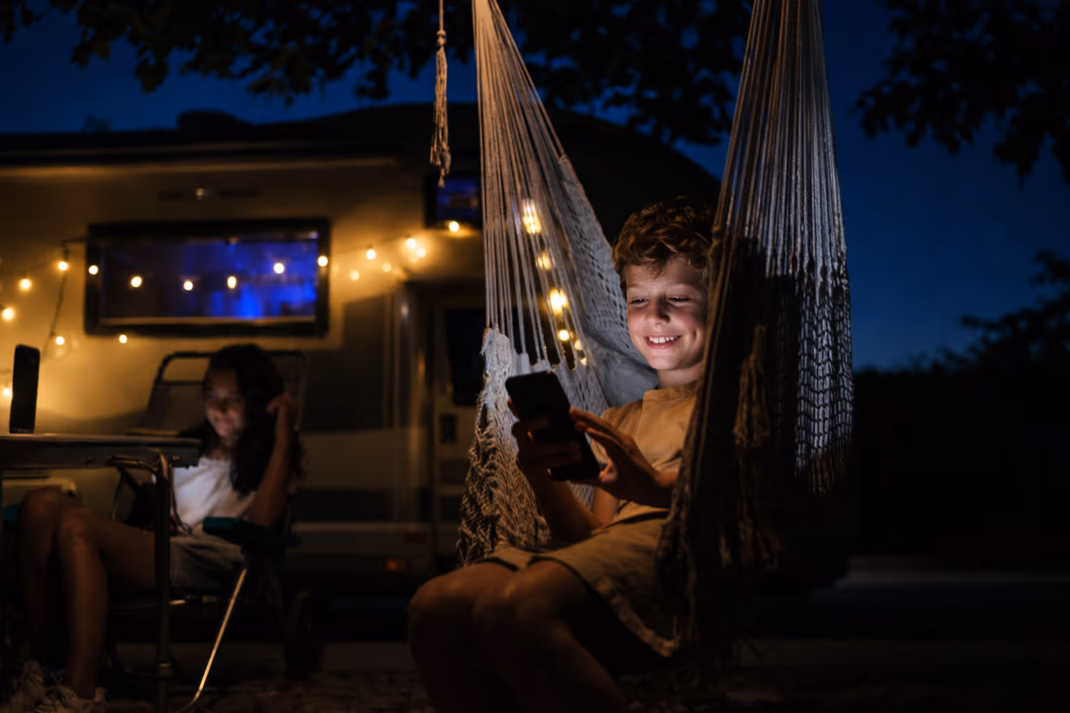 Campervan campsite scene with outdoor seating and evening lighting