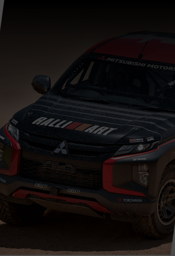 Black Mitsubishi off-road vehicle with Ralliart branding on the hood and yokohama and endless logos on the front bumper, driving on a dirt surface.