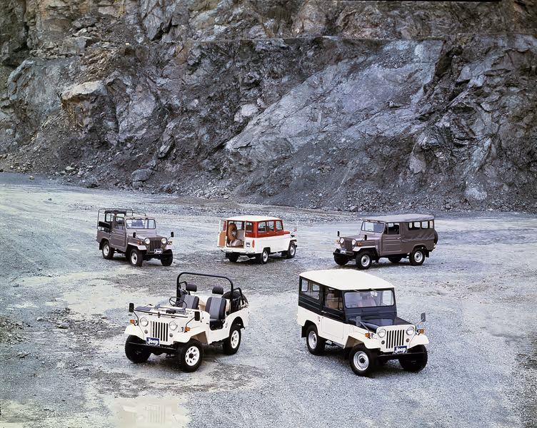 Four Mitsubishi SUVs parked on grass with large trees in the background, featuring blue, white, red, and white models.
