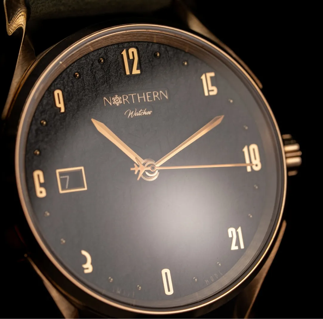 Close-up of a Northern Watches wristwatch with gold hands and numerals on a dark textured dial showing the time 10:10:19 and date 7.