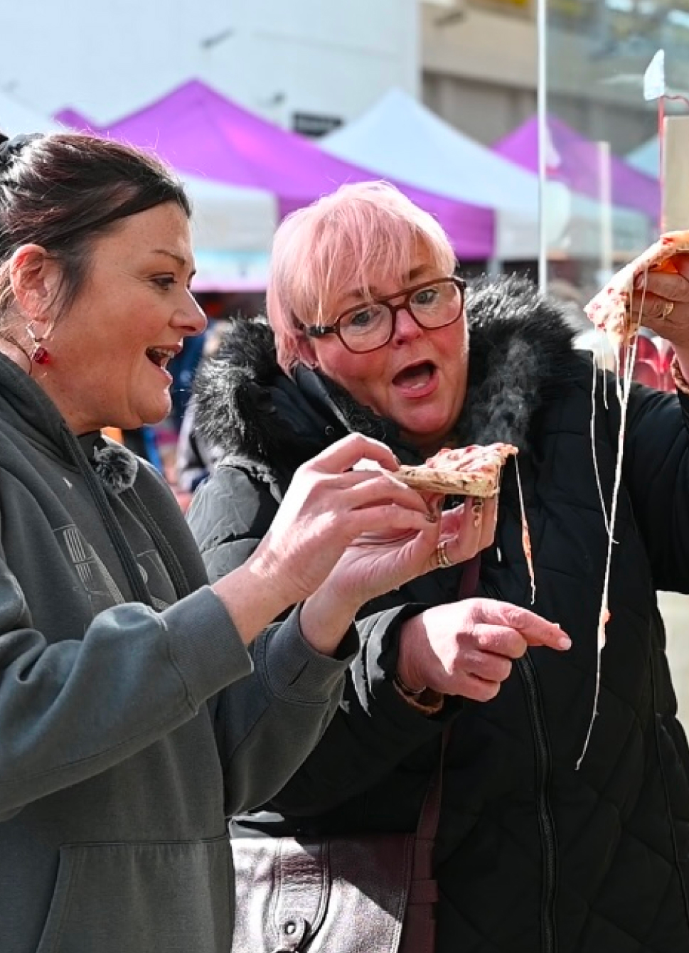 Two friends laughing and having pizza at table