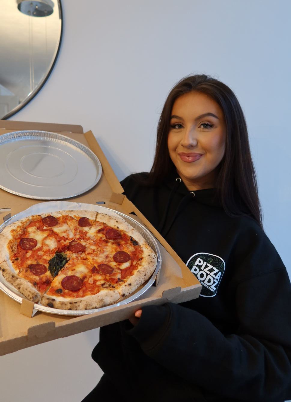 A young woman eating a piece of pizza in the car