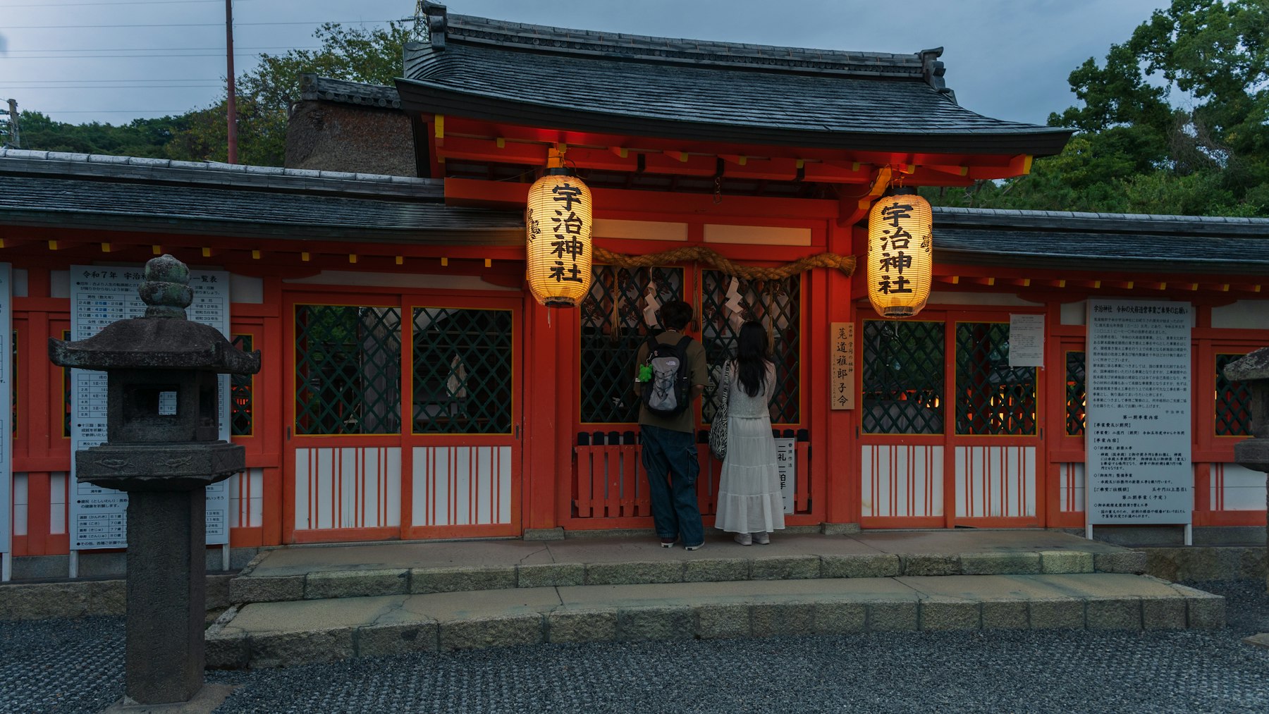Visitors in front of a lantern-lit shrine in Uji, Kyoto