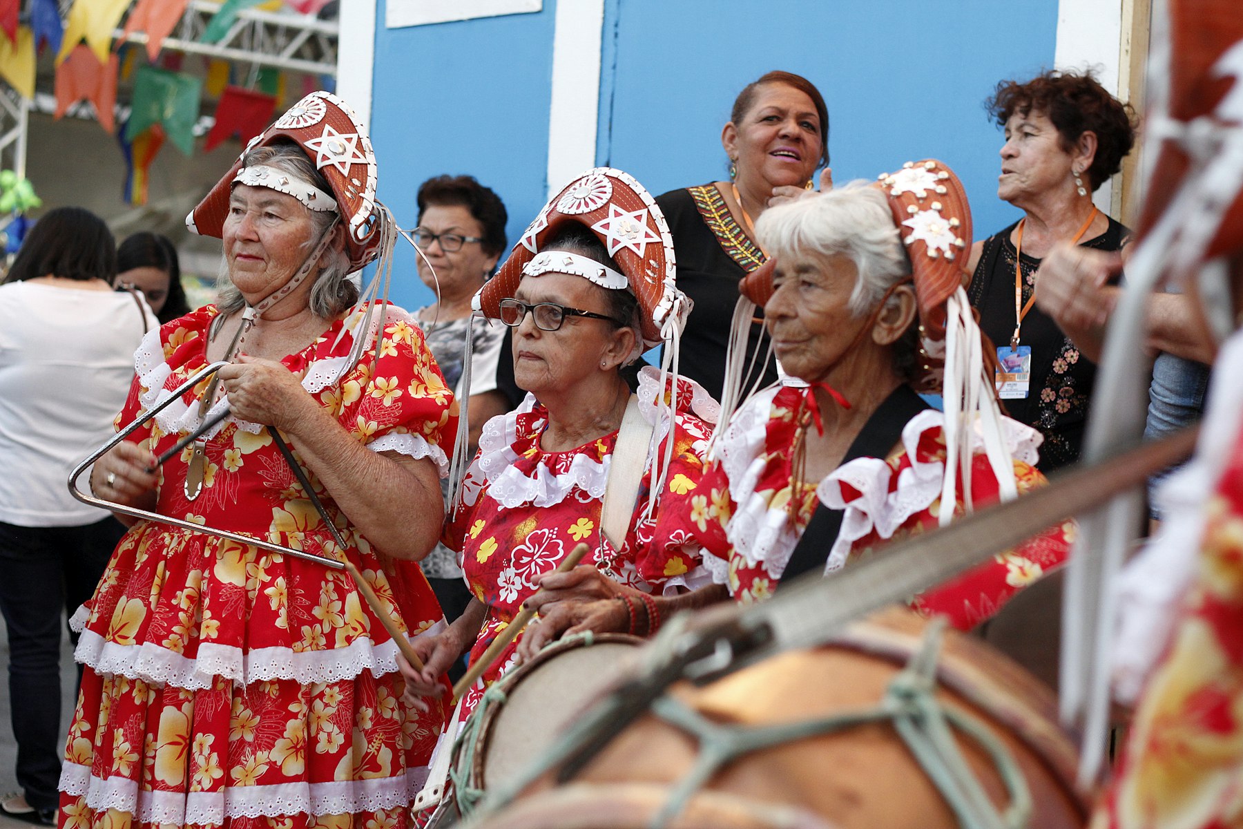 Mujeres con vestidos de fiesta rojos estampados y un tambor en una celebración callejera en Brasil