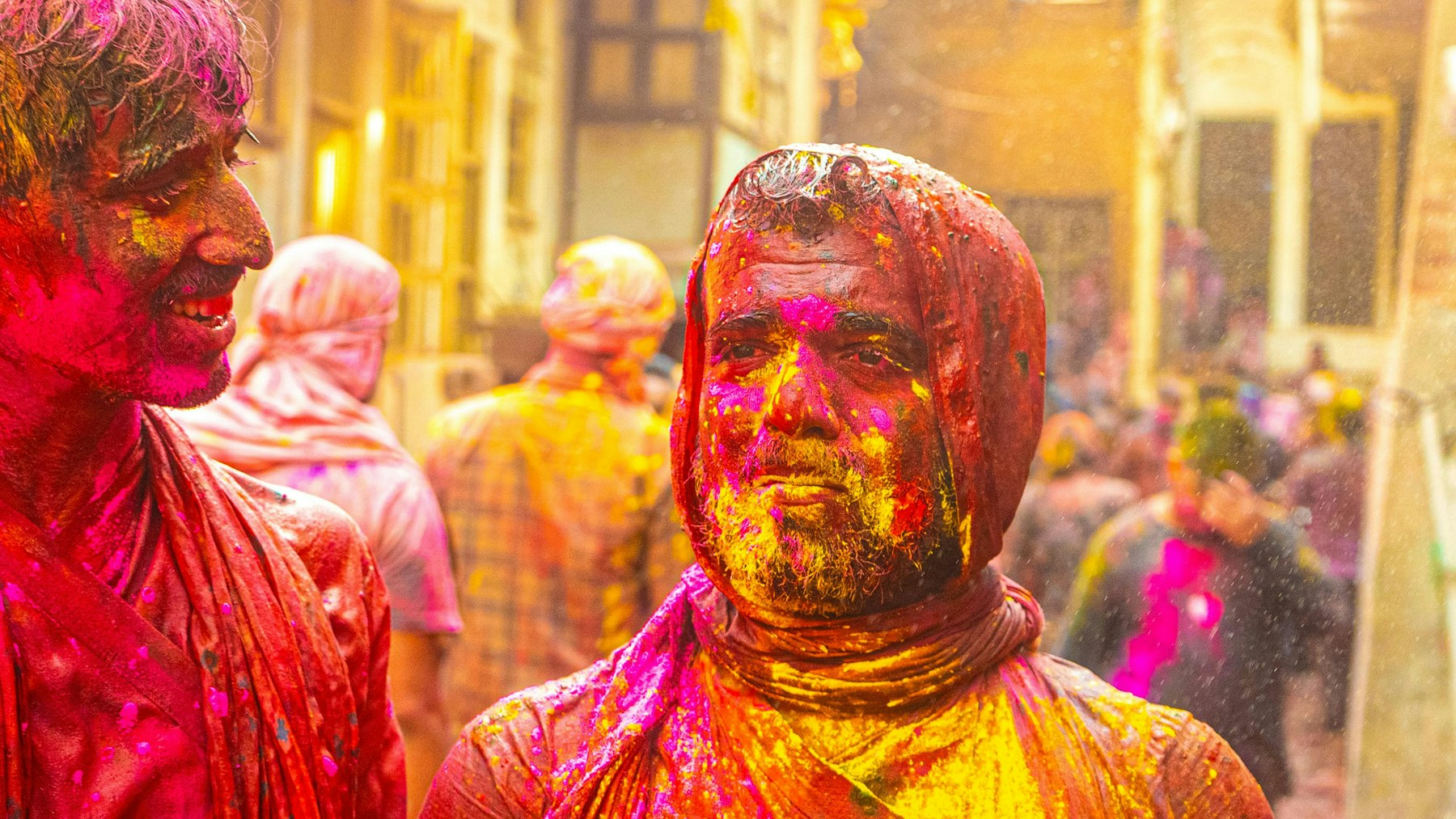 Mit Farbpulver bedeckte Menschen feiern Holi in Vrindavan
