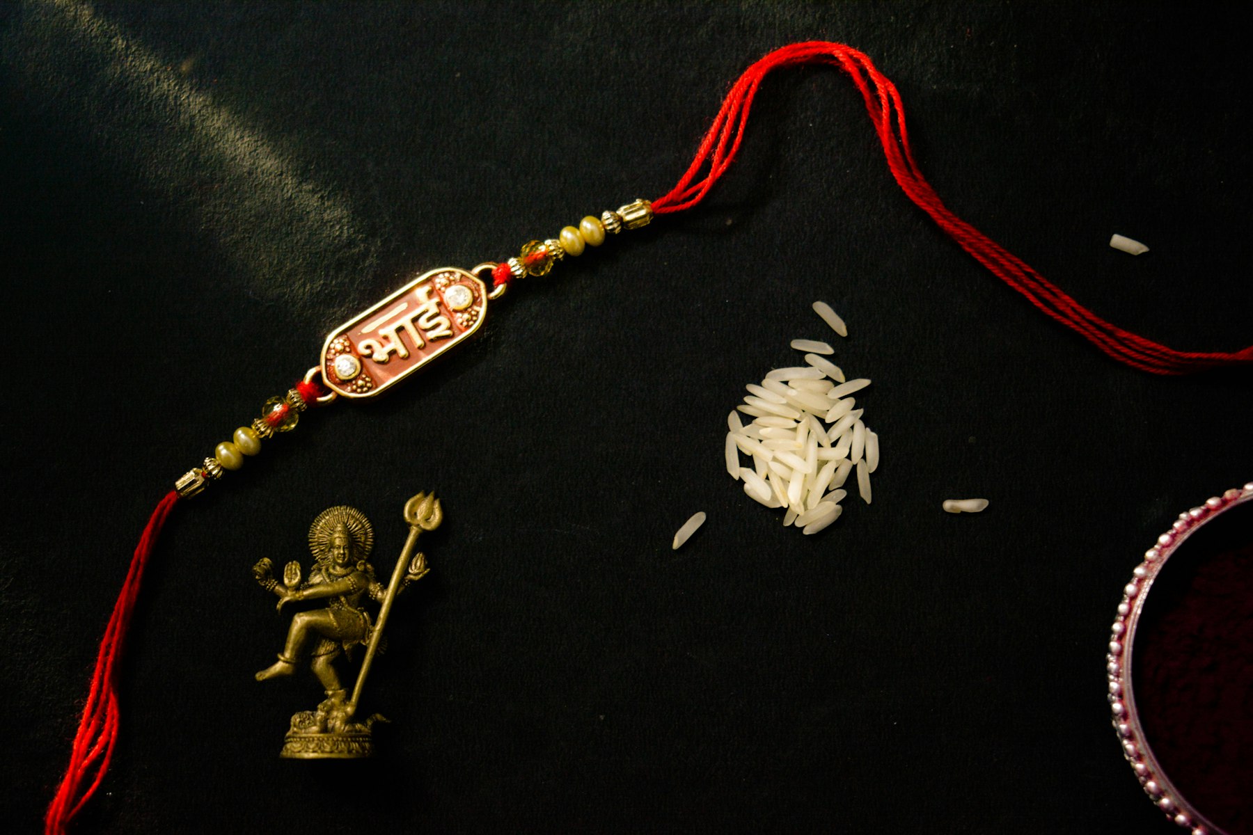 Un hilo rakhi con cuentas junto a granos de arroz