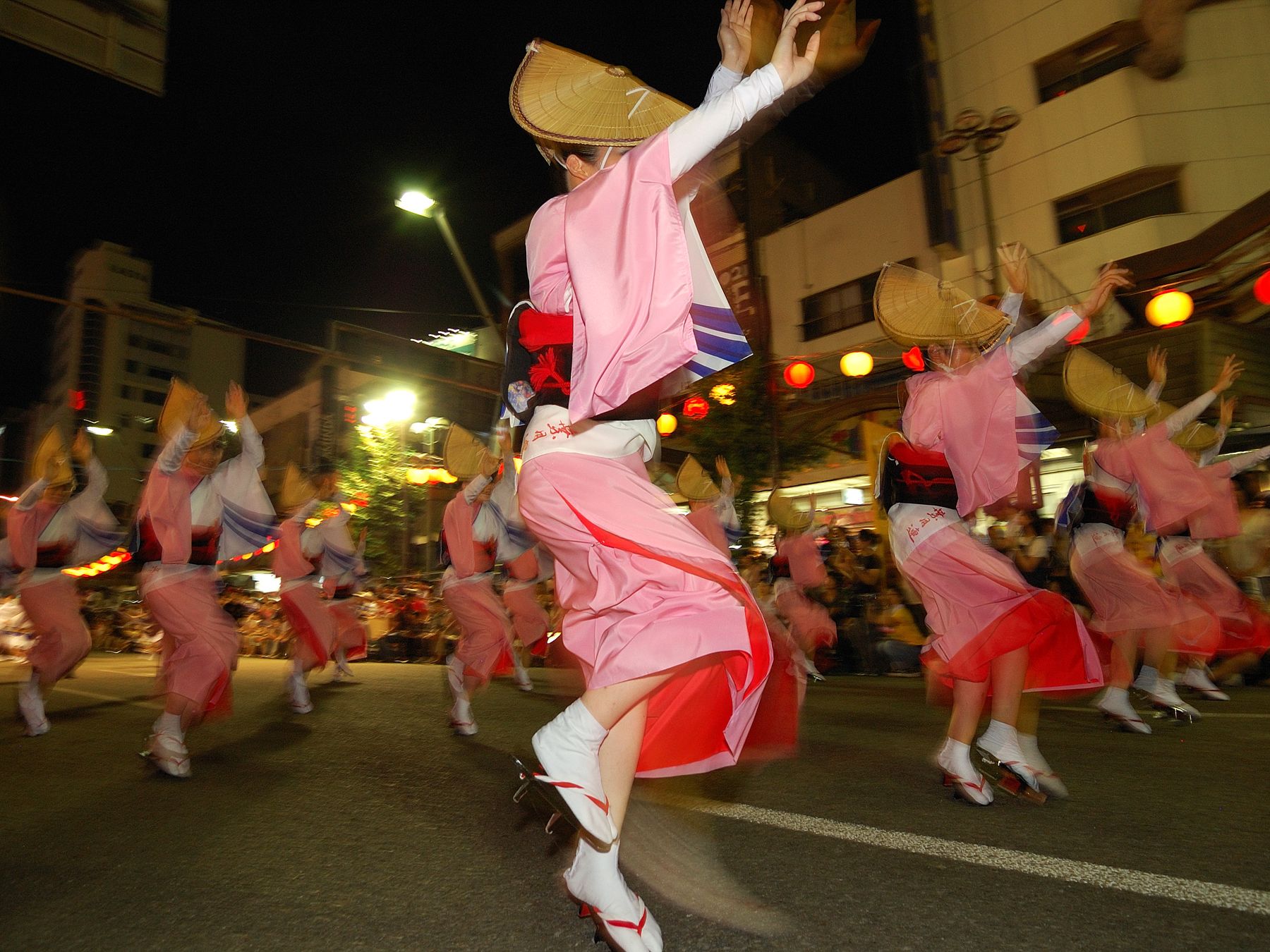 Tanzgruppe in rosa Yukata und mit Strohhüten beim nächtlichen Awa Odori in Tokushima während Obon