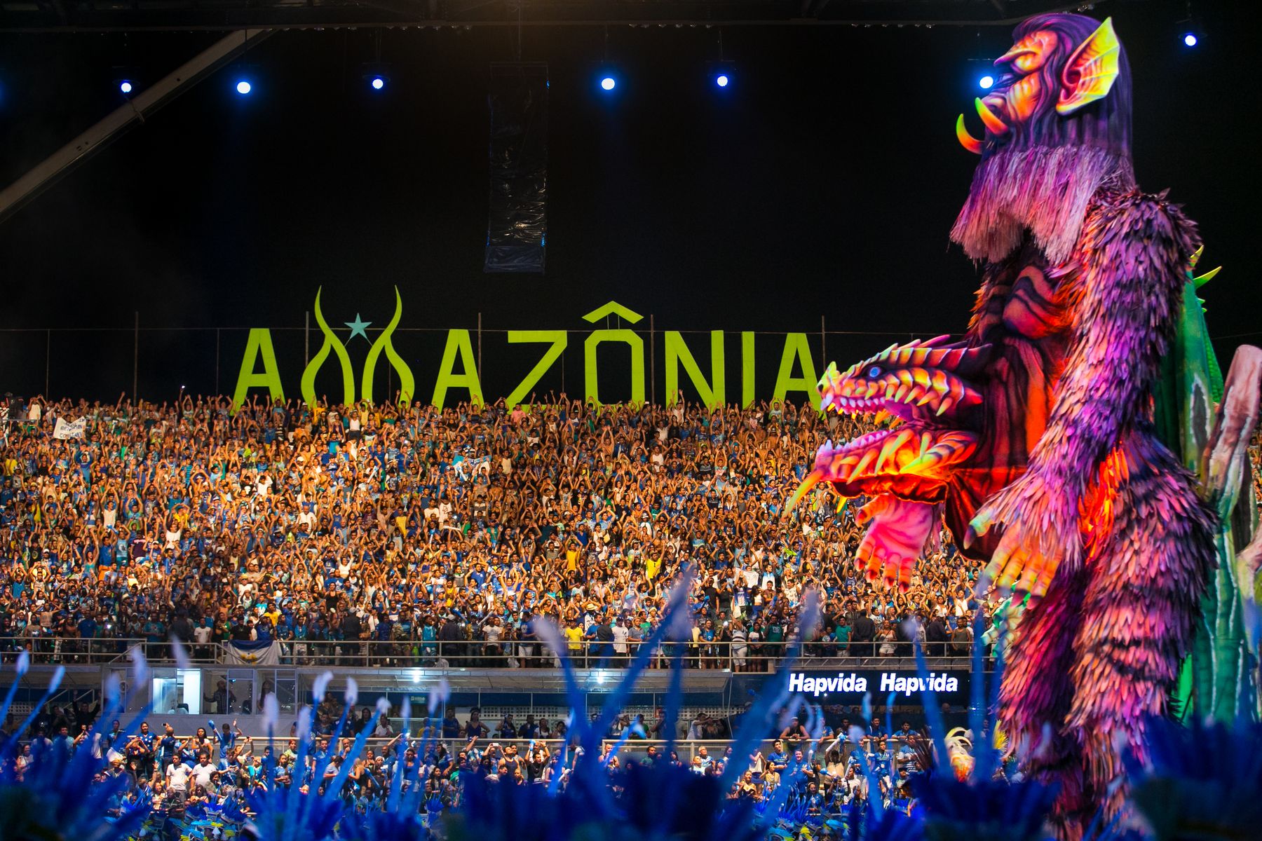 A giant allegorical figure and a packed Bumbódromo crowd during Boi Caprichoso's performance at the Parintins Festival