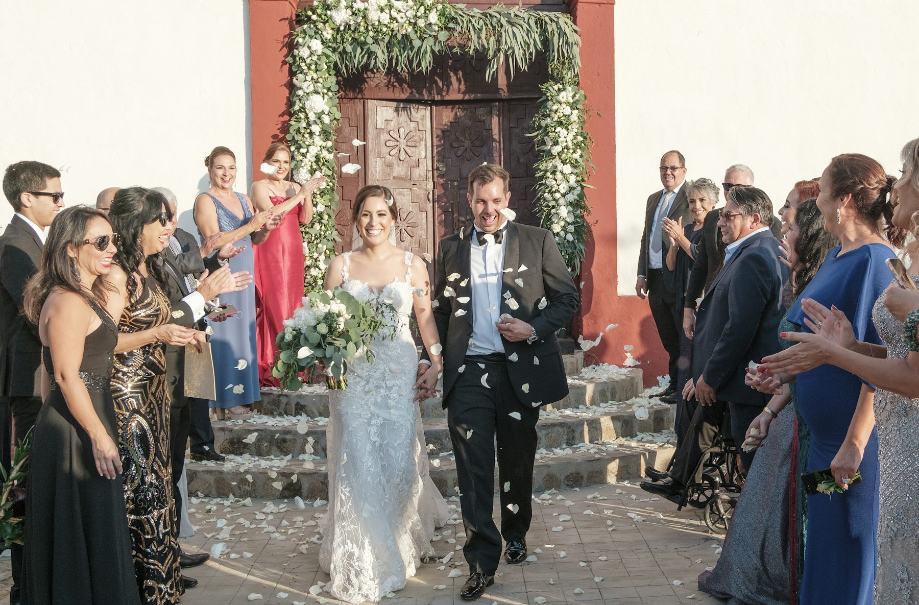 A bride and groom leave the church between applauding guests