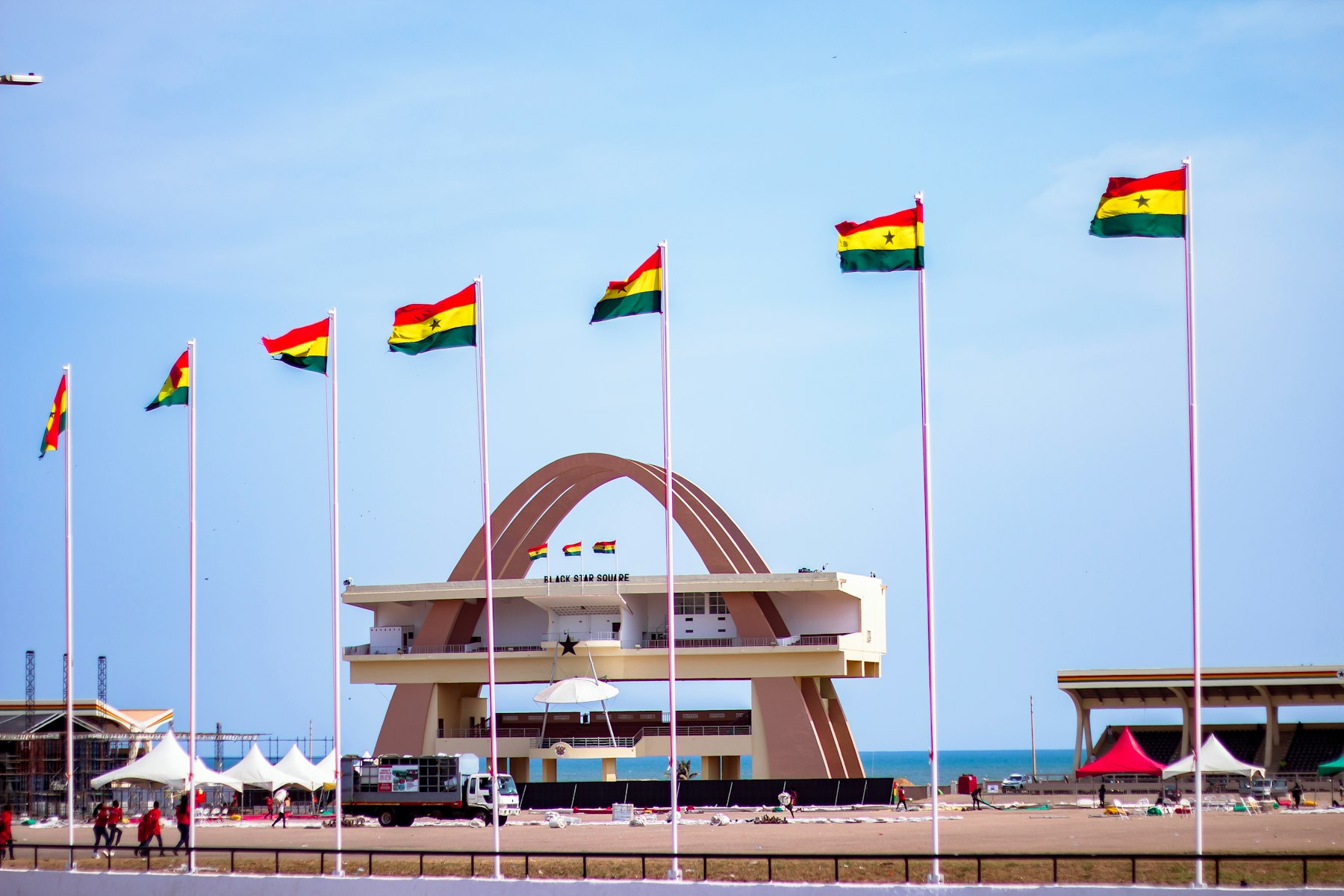 Ghanaian flags flying on tall poles in front of the Black Star Gate at Black Star Square in Accra