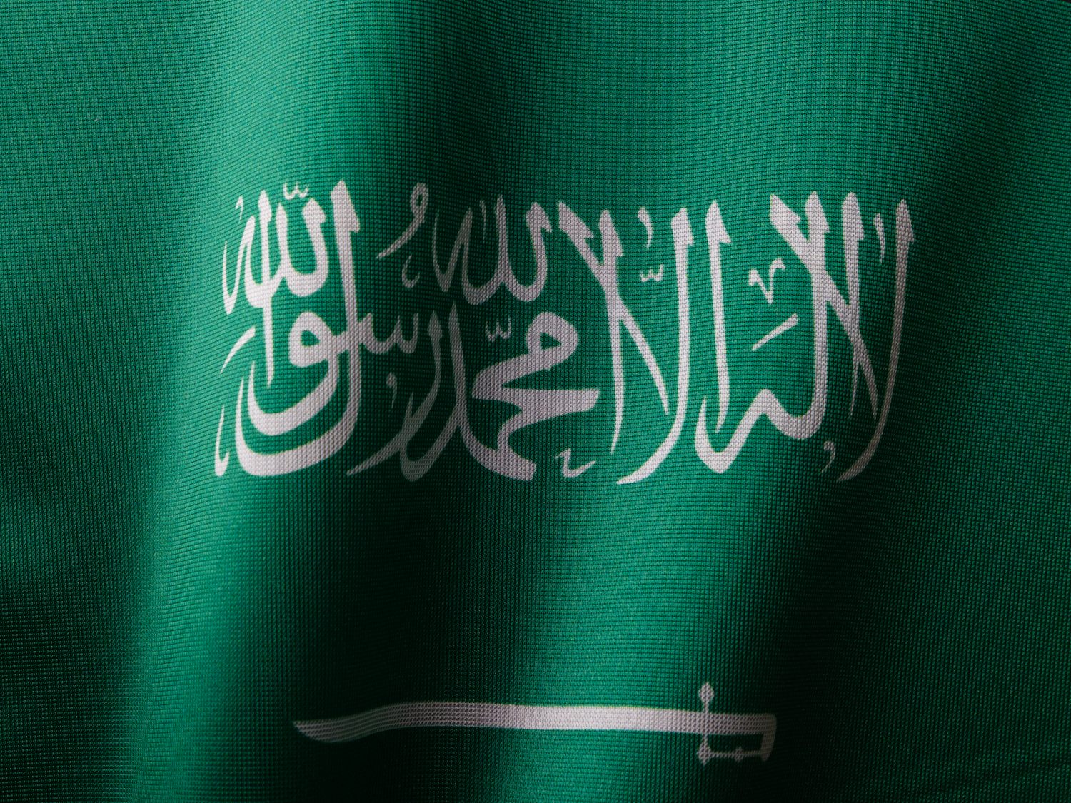Close-up of the green flag of Saudi Arabia with its white script and sword