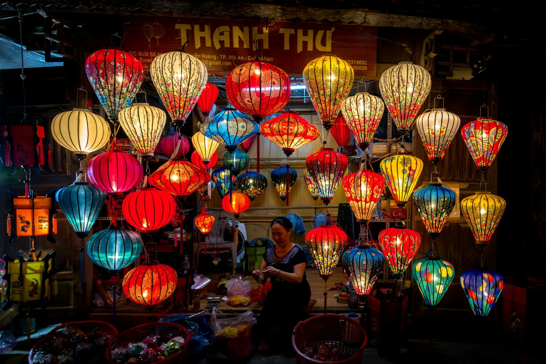 Coloridos farolillos de seda iluminados en una tienda de faroles de Hội An