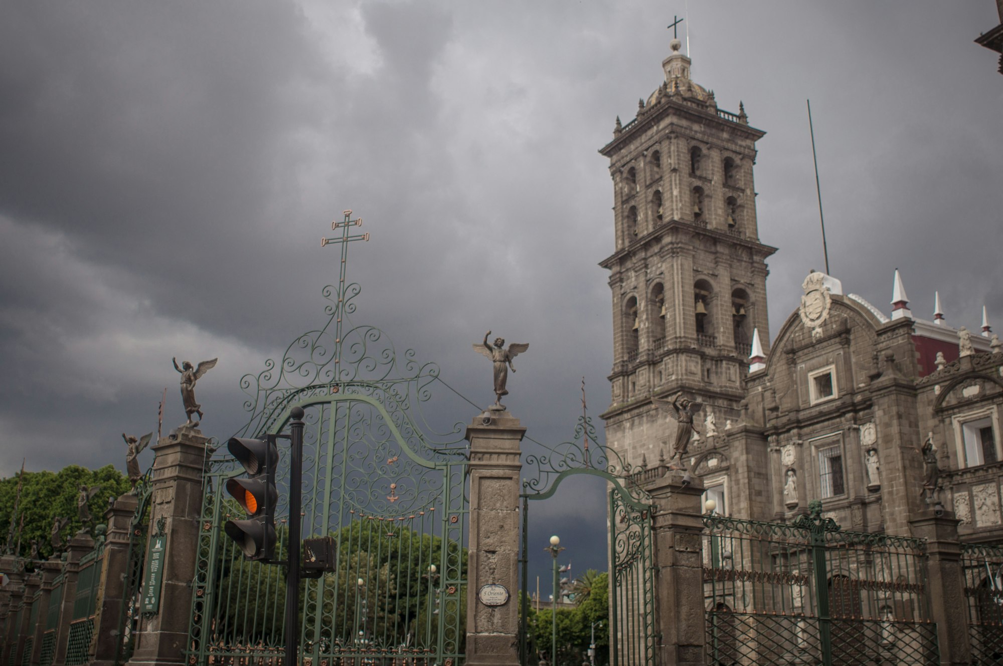 Glockenturm der Kathedrale von Puebla hinter dem schmiedeeisernen Tor unter einem Gewitterhimmel
