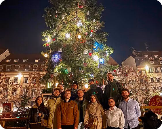 The Pixacare team posing in front of Strasbourg's large Christmas tree at night in the city.