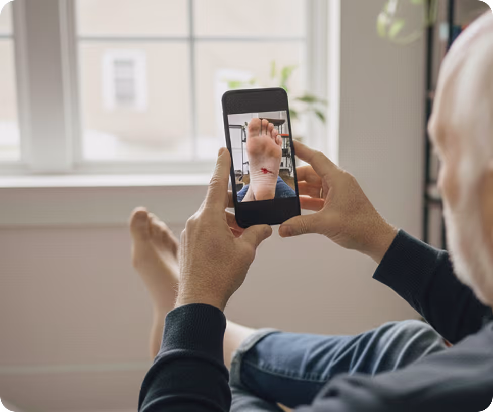 A man taking a picture of a bleeding wound on the sole of his foot with the Pixacare app.
