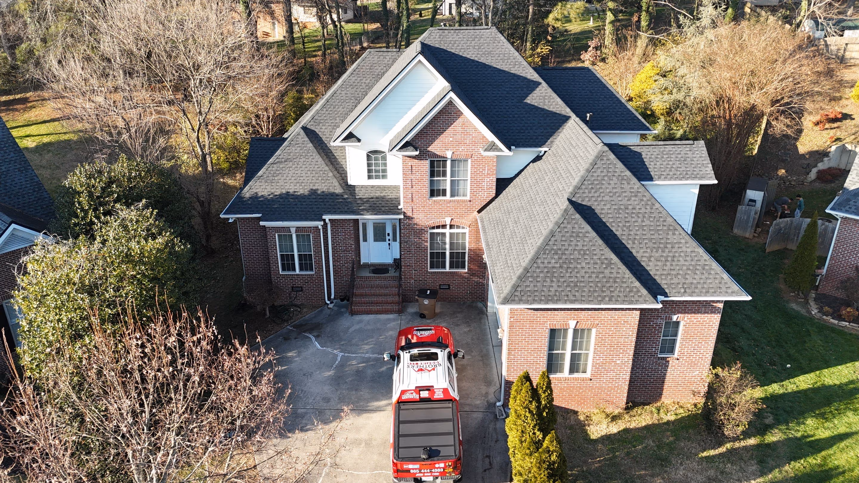Completed architectural shingle roof beside a Best Brothers Roofing service truck in Knoxville.
