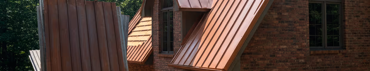 Close-up of a brick house with several brown metal awnings over windows and a door.