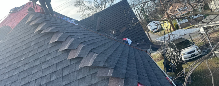 Close-up of roof with lifted and missing shingles exposing the underlayment beneath