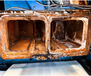 Close-up of a rusty, corroded metal machine component with two rectangular hollow sections.