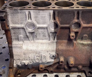 Half of a metal engine block cleaned to show contrast between rusted and restored surfaces.