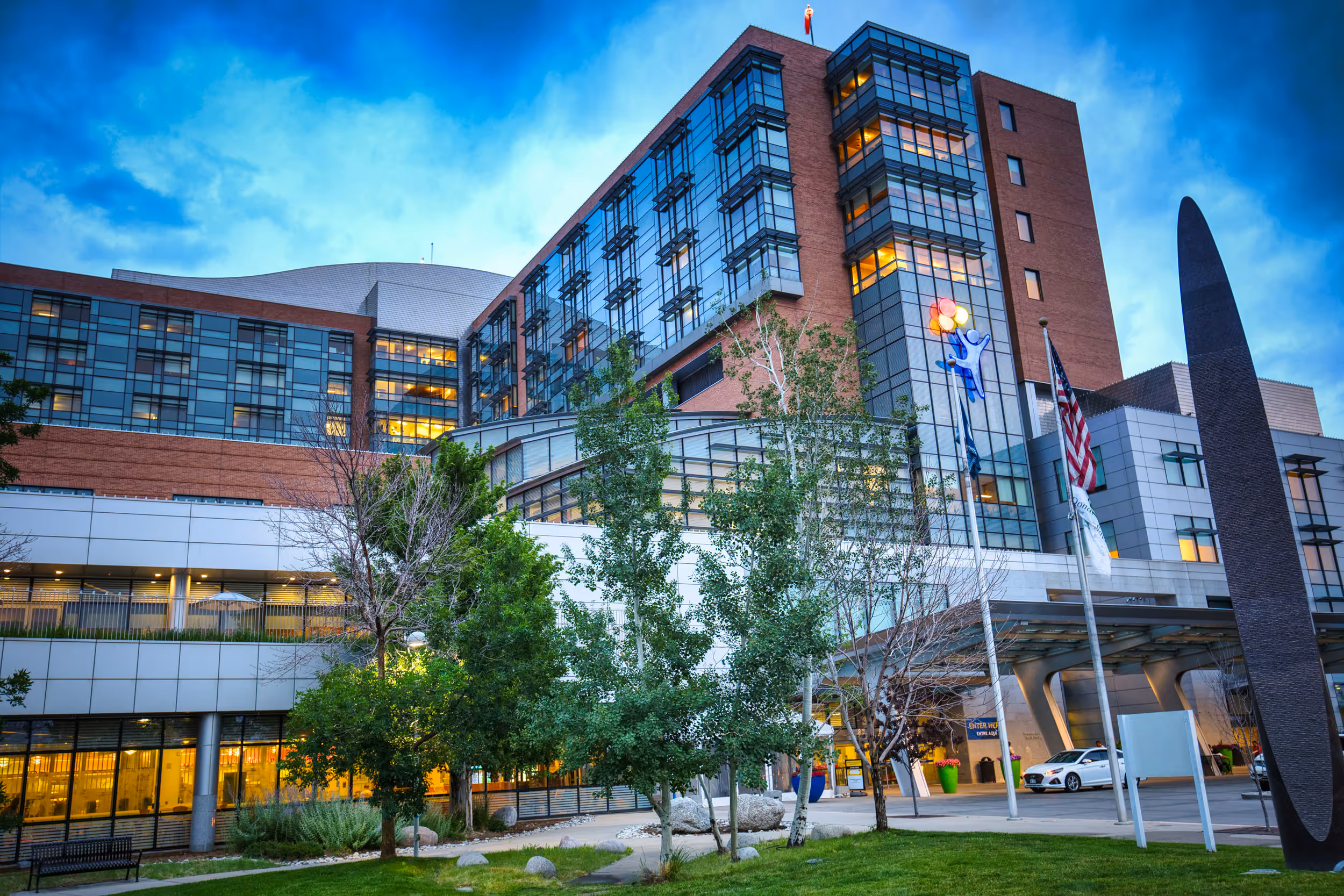 3D model of an airport terminal with glass walls, a control tower, airplane at the gate, and surrounding service vehicles.