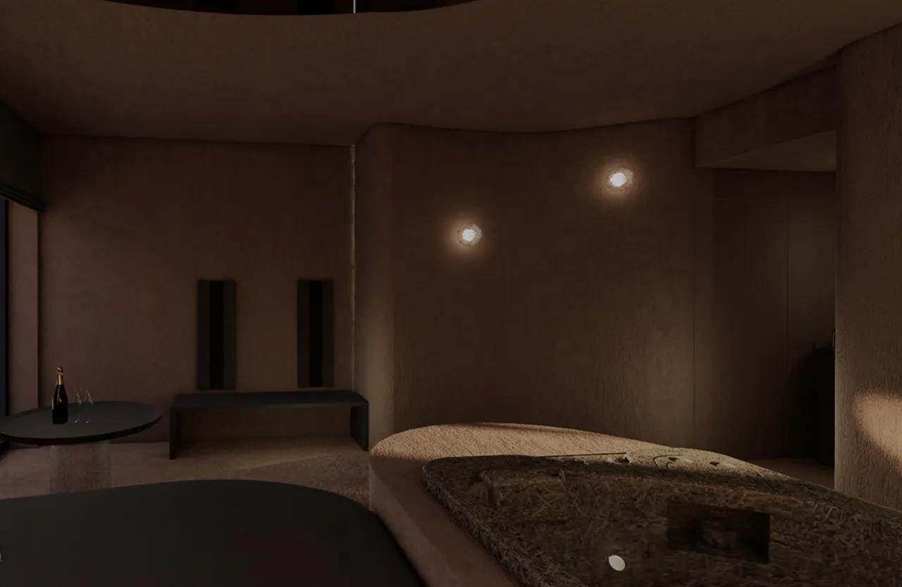 Chambre minimaliste avec un lit rond, un banc noir, une table avec une bouteille de champagne et deux verres, murs marron et lumières murales.