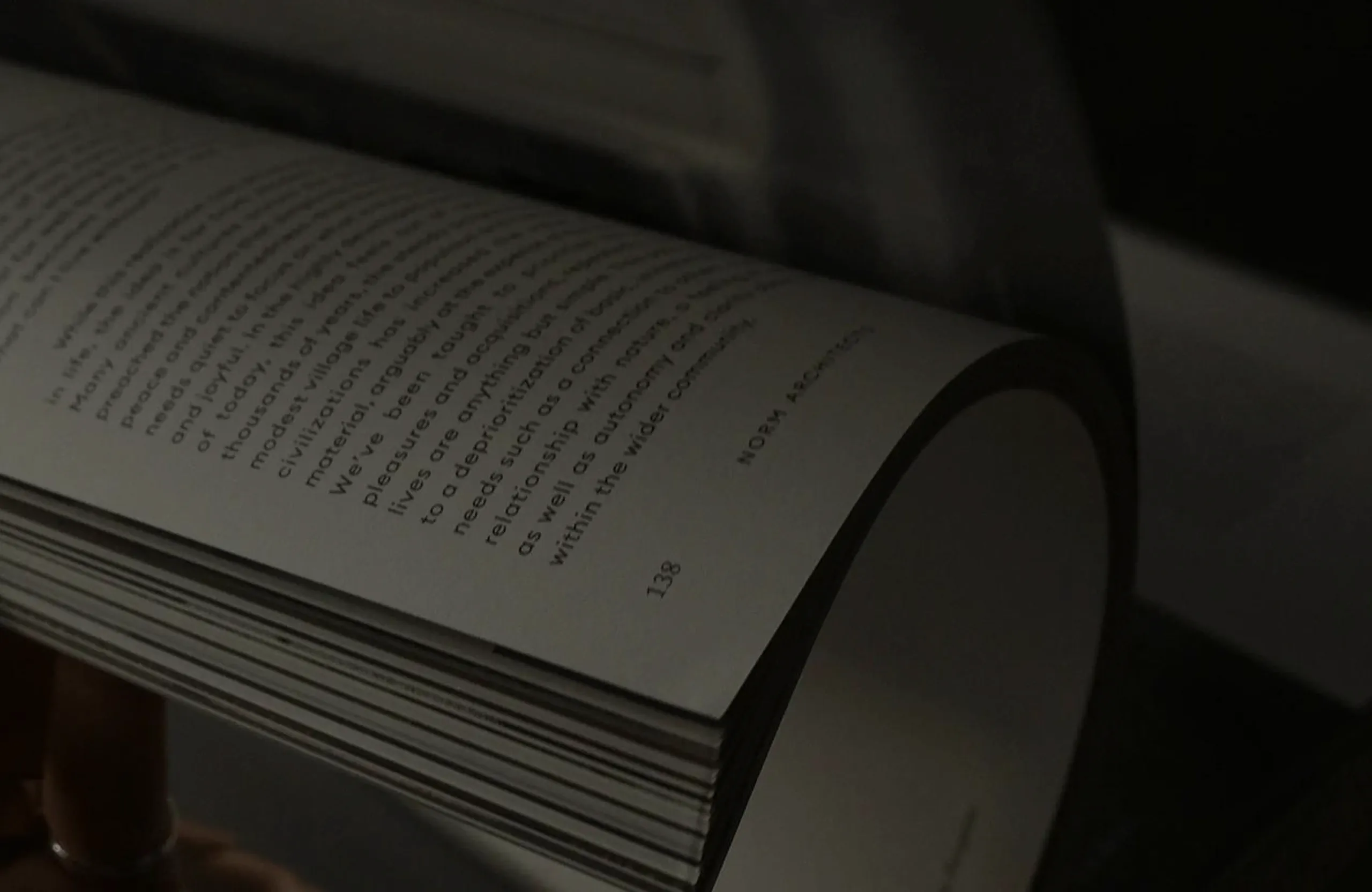 Gros plan d'une main tenant un livre ouvert avec du texte imprimé en anglais sur une page légèrement courbée.