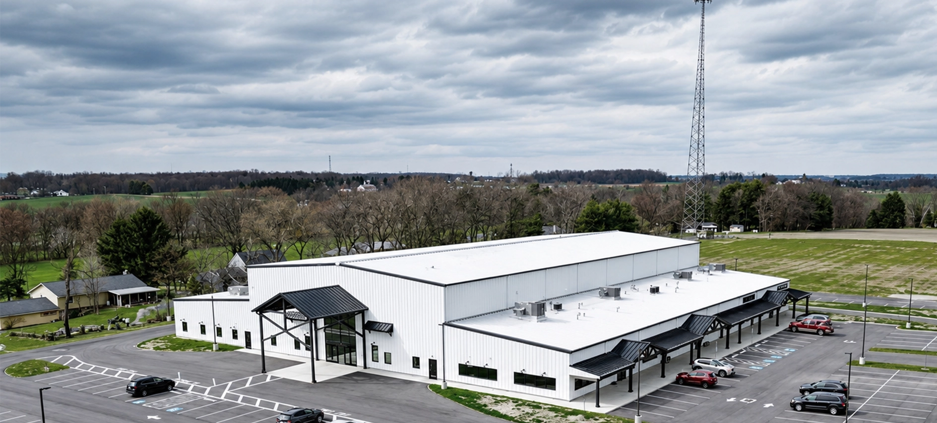 Drone short of a white commercial building and parking lot