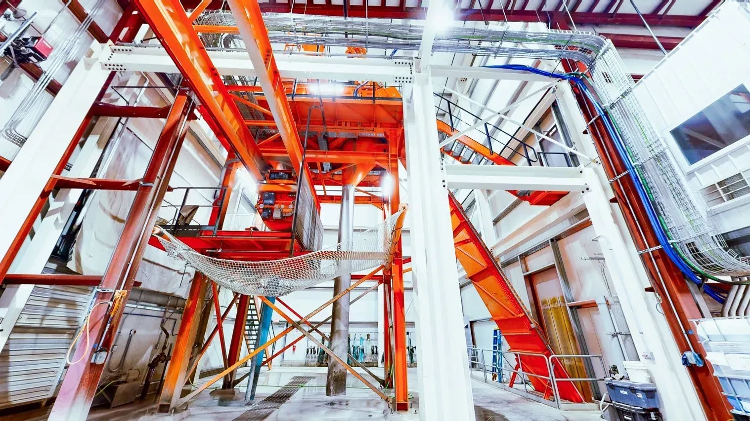 Interior of Casa Di Sassi manufacturing tower with orange steel structural framing, catwalks, and overhead piping