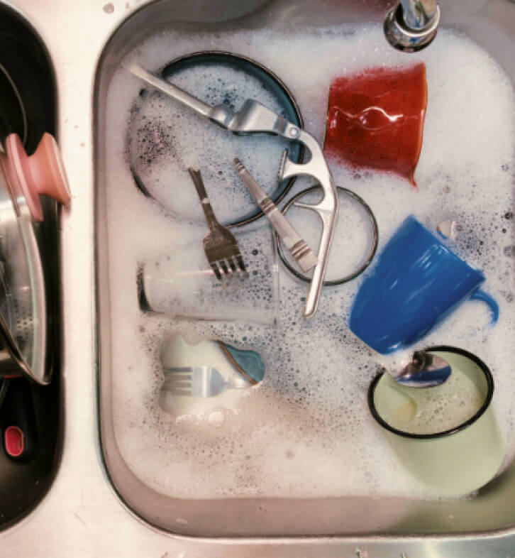 Photo of dishes piled in a sink full of water