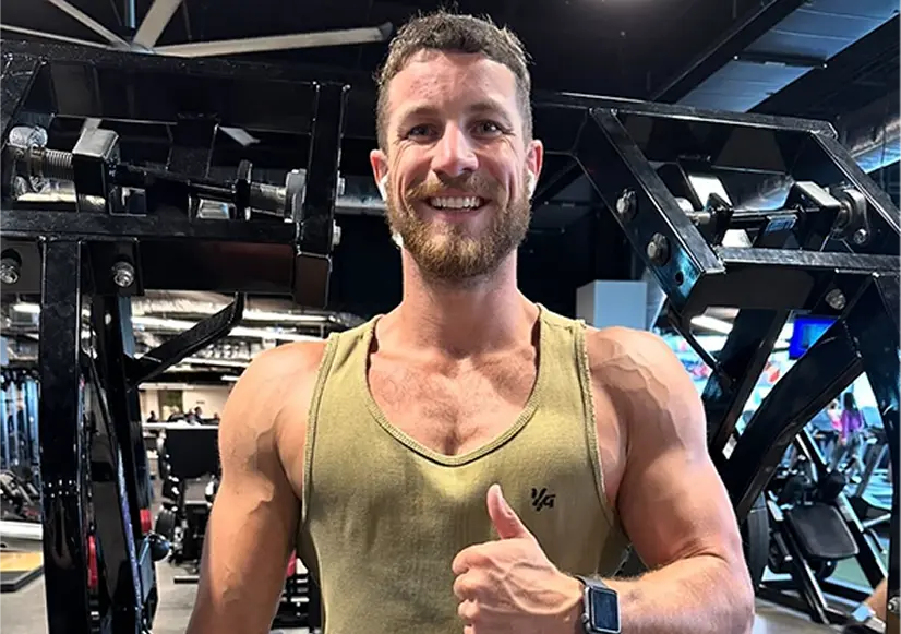Fitness coach Kyle demonstrating strength and muscle development in a gym environment