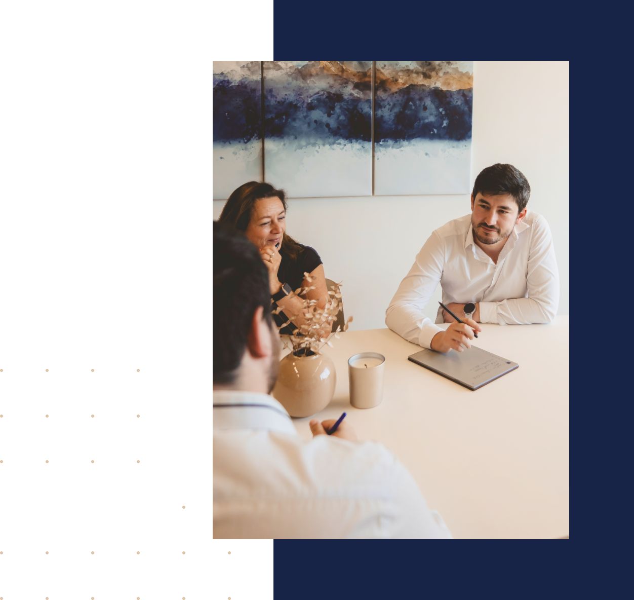 Trois personnes en réunion autour d'une table blanche avec un vase et une bougie, une œuvre d'art abstraite bleue est accrochée au mur.