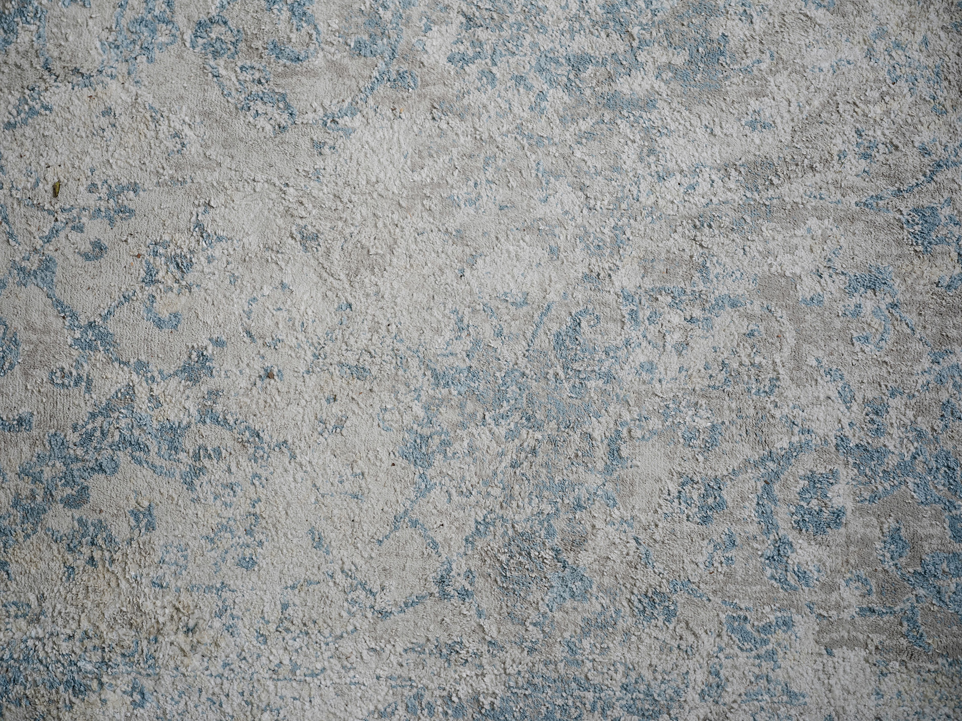 Close-up of a textured, patterned rug with beige and light blue colors.