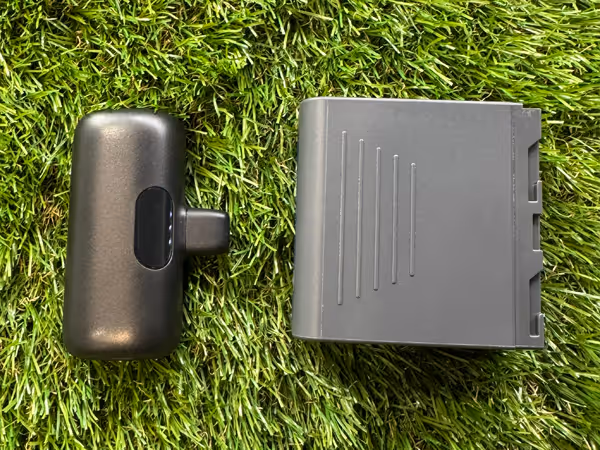 Two black rechargeable lithium-ion batteries on green artificial grass surface.