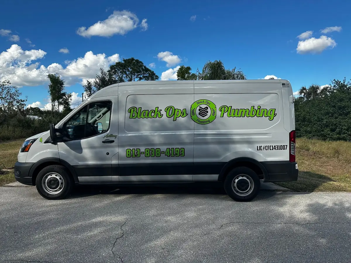 White Black Ops Plumbing service van parked on a road with green logo and phone number 813-838-4193 on the side under a blue sky with clouds.