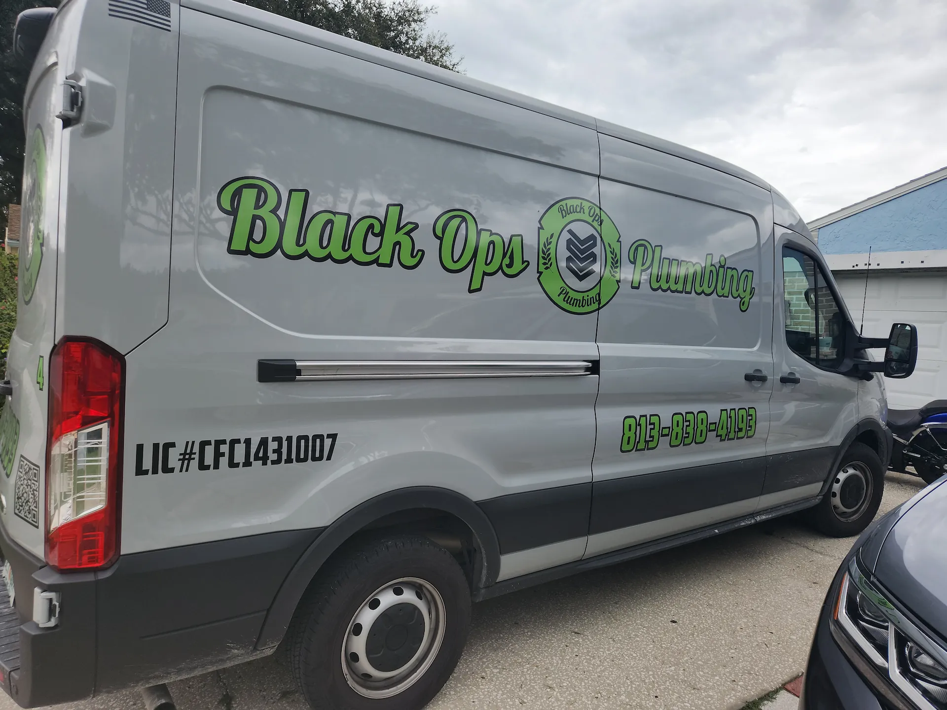 Gray Black Ops Plumbing service van with green and black lettering, phone number 813-838-4193, and license number CFC1431007.