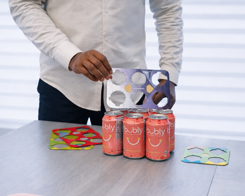 An image of a man displaying printing material for soda cans.
