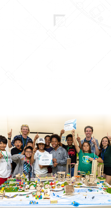 Group of children and two adults standing behind a colorful architectural model, holding certificates and smiling.