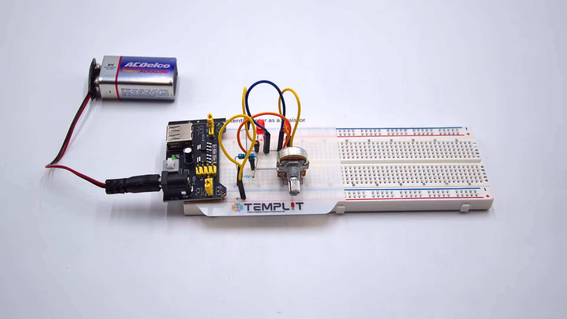 Electronic breadboard circuit with a potentiometer, yellow and blue jumper wires, a resistor, a 9V battery, and a connected black power module labeled TEMPLIT.