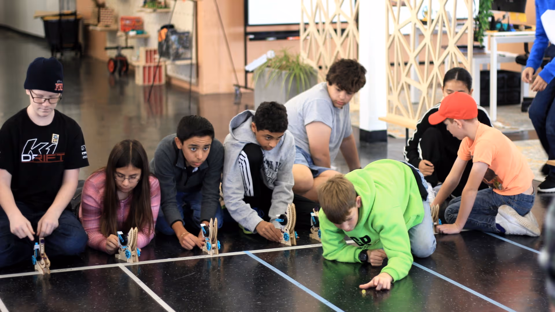 Boy working on a cardboard electronics project labeled 'Let it go' on a classroom table.