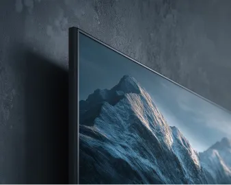 Close-up of a flat-screen TV mounted on a dark textured wall displaying a mountain scene.