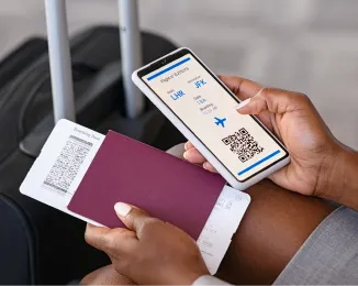 Person holding a smartphone showing a digital boarding pass and a passport with a boarding ticket