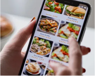 Person using a smartphone app to browse various food delivery options with images and ratings.