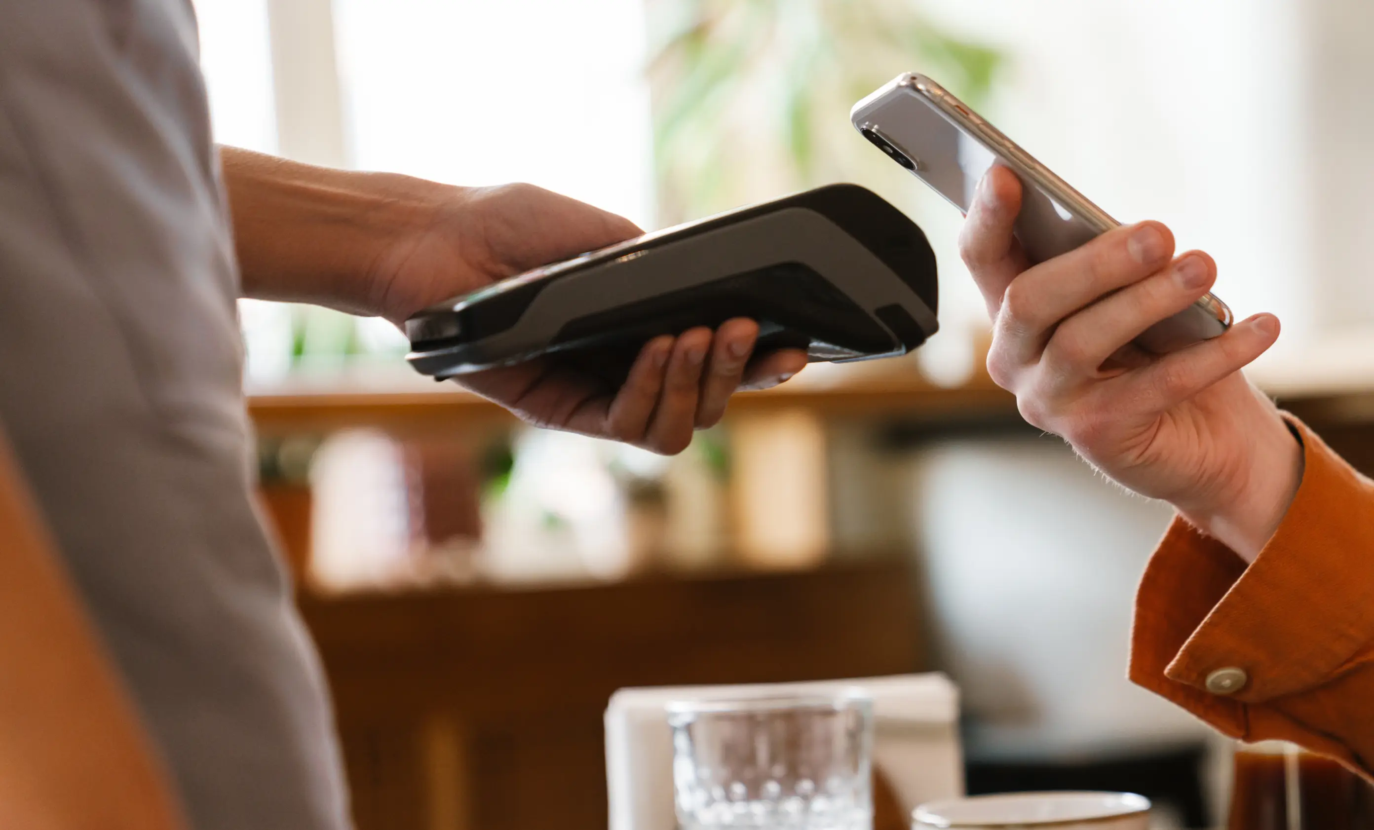 Person making a contactless payment by holding a smartphone over a payment terminal.